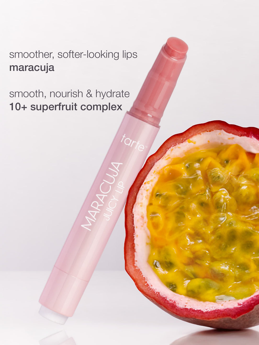 A pink lip product labeled MARACUJA JUICY LIP lies next to an open passion fruit. Text reads: smoother, softer-looking lips maracuja smooth, nourish & hydrate 10+ superfruit complex.