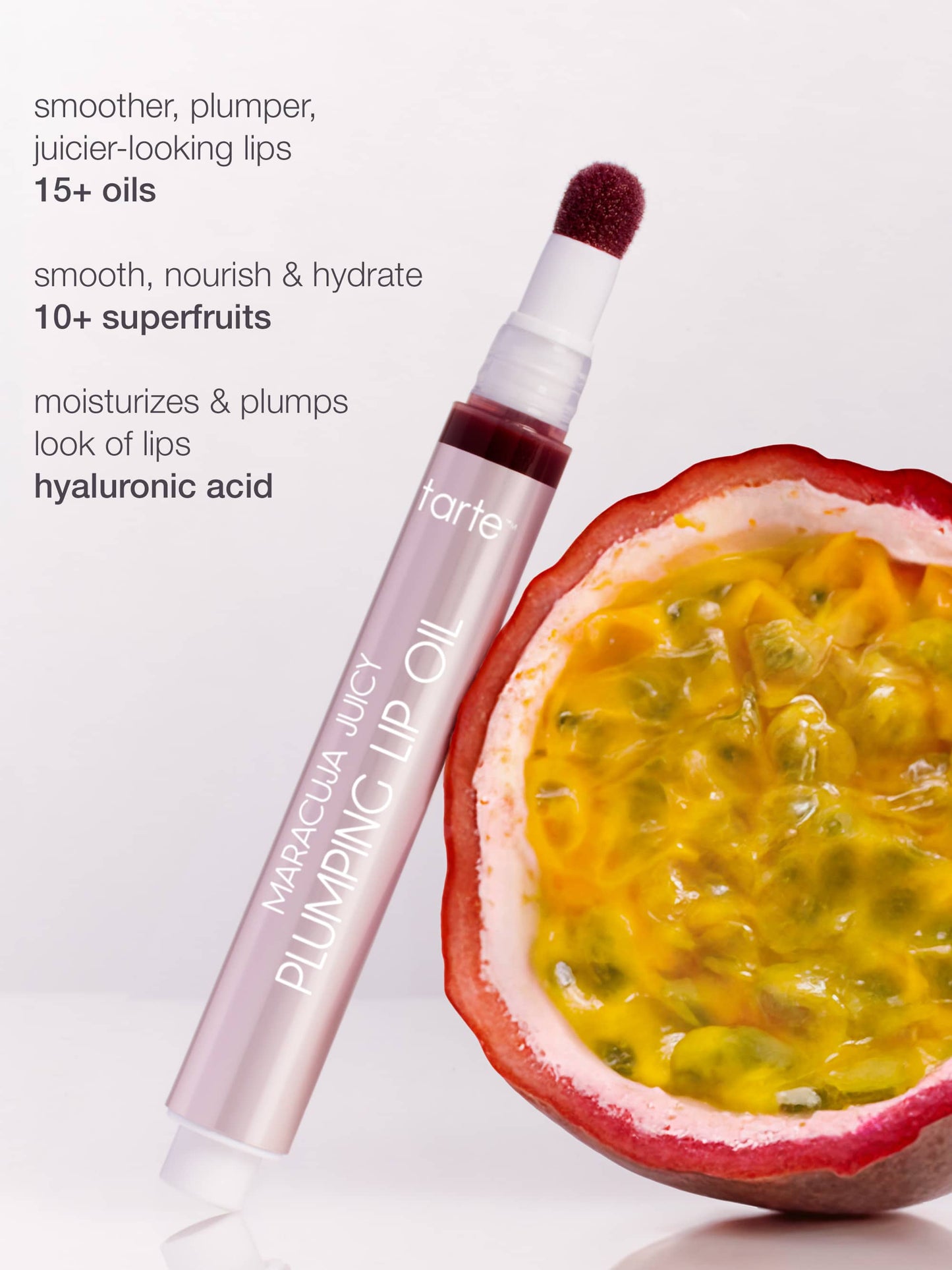 Tarte Maracuja Juicy Plumping Lip Oil with a passion fruit on a white background