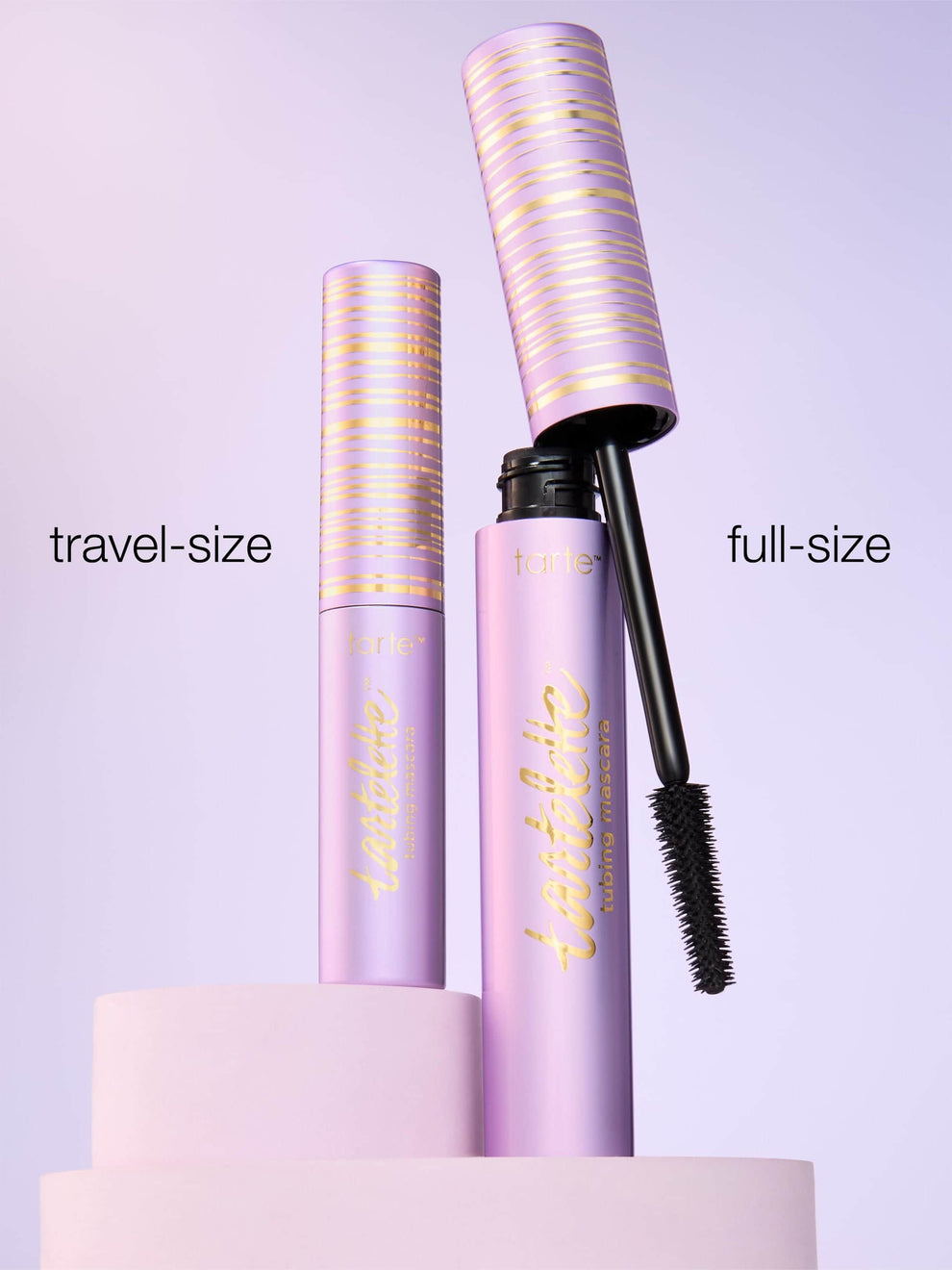 Two purple mascara tubes, one labeled 'travel-size' and the other 'full-size', on a light purple background.