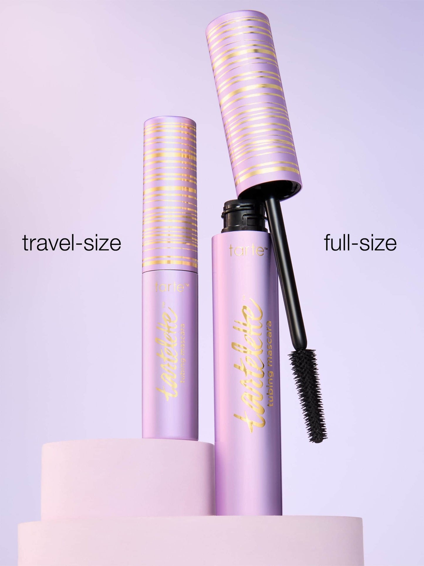 Two purple mascara tubes, one labeled 'travel-size' and the other 'full-size', on a light purple background.