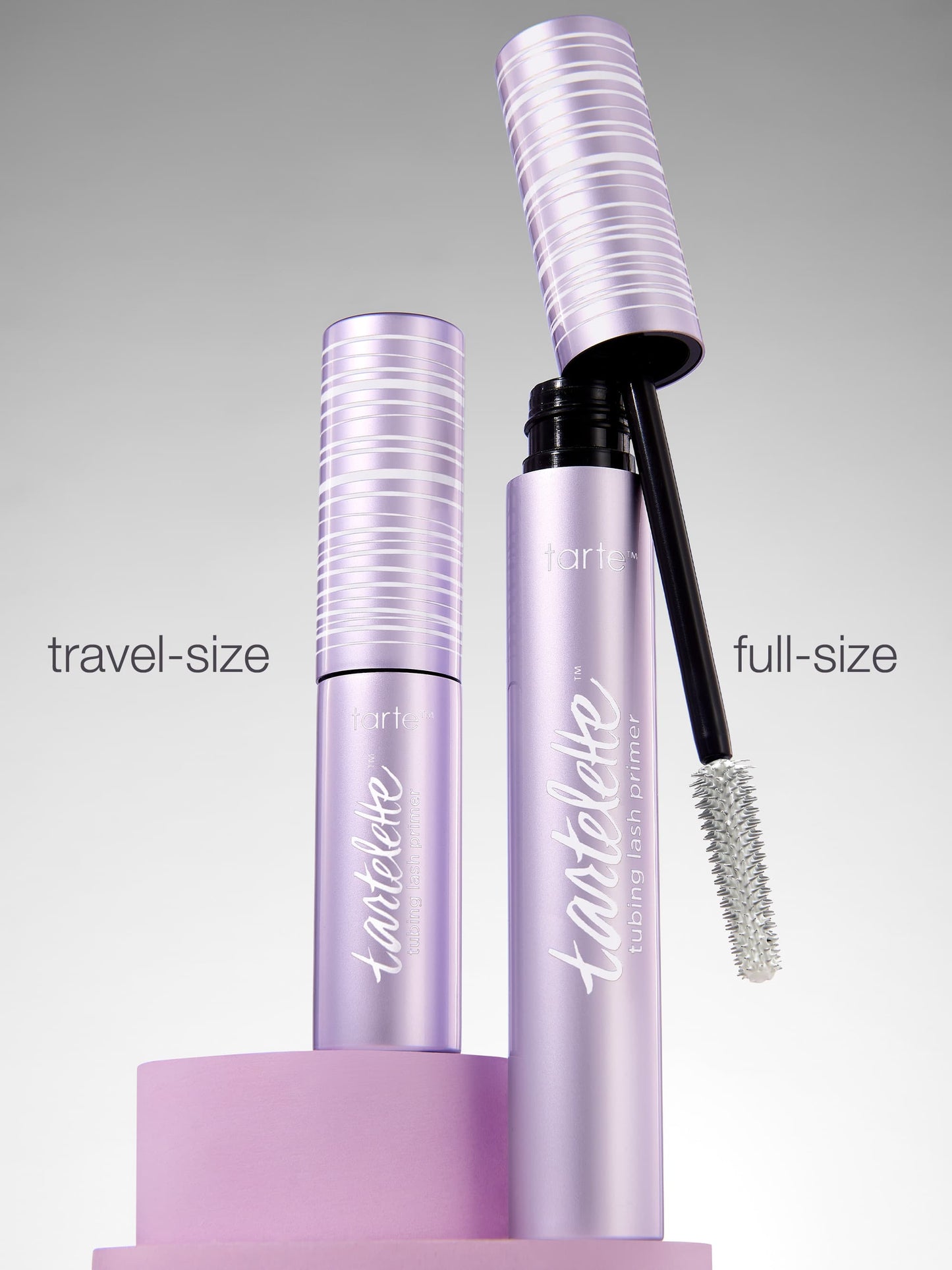 Full-size and travel-size mascara bottles with lashes on a gray background