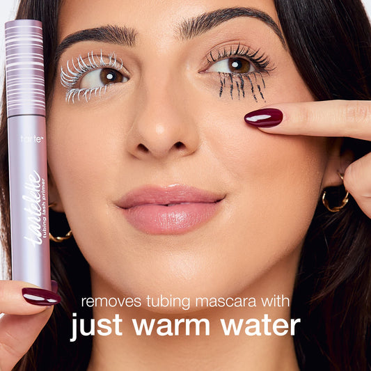 A person holds Tarte Cosmetics Lash Paint in front, with white mascara on one eye and black mascara on another, smiling. Text: removes tubing mascara with just warm water.