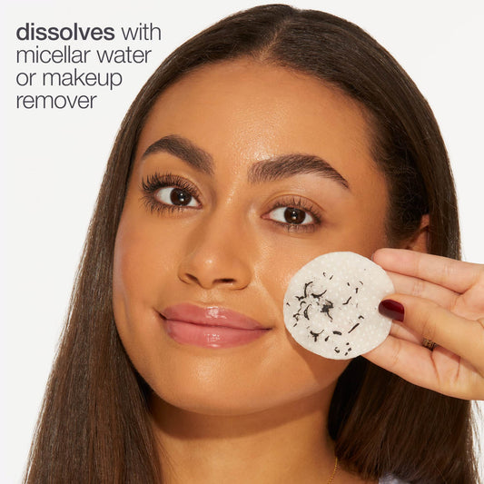 A person holds a makeup remover pad near their face, demonstrating makeup removal. Text reads, dissolves with micellar water or makeup remover. The background is plain white.