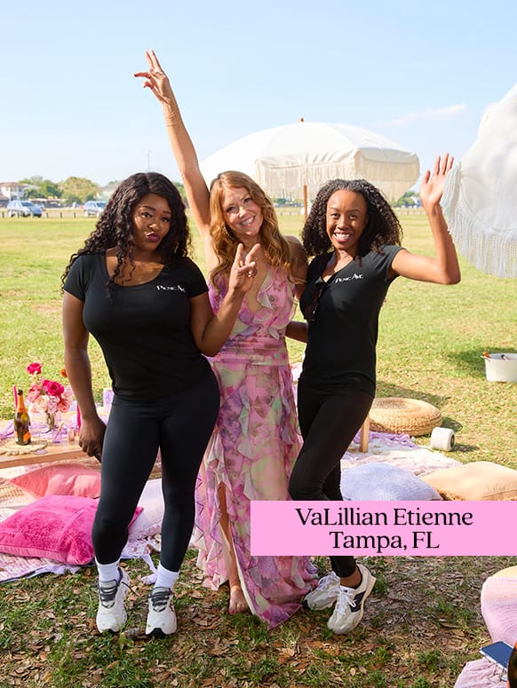 Three people pose playfully on a grassy area with picnic items and umbrellas. Two wear black shirts, one a floral dress. Text reads: VaLillian Etienne Tampa, FL.