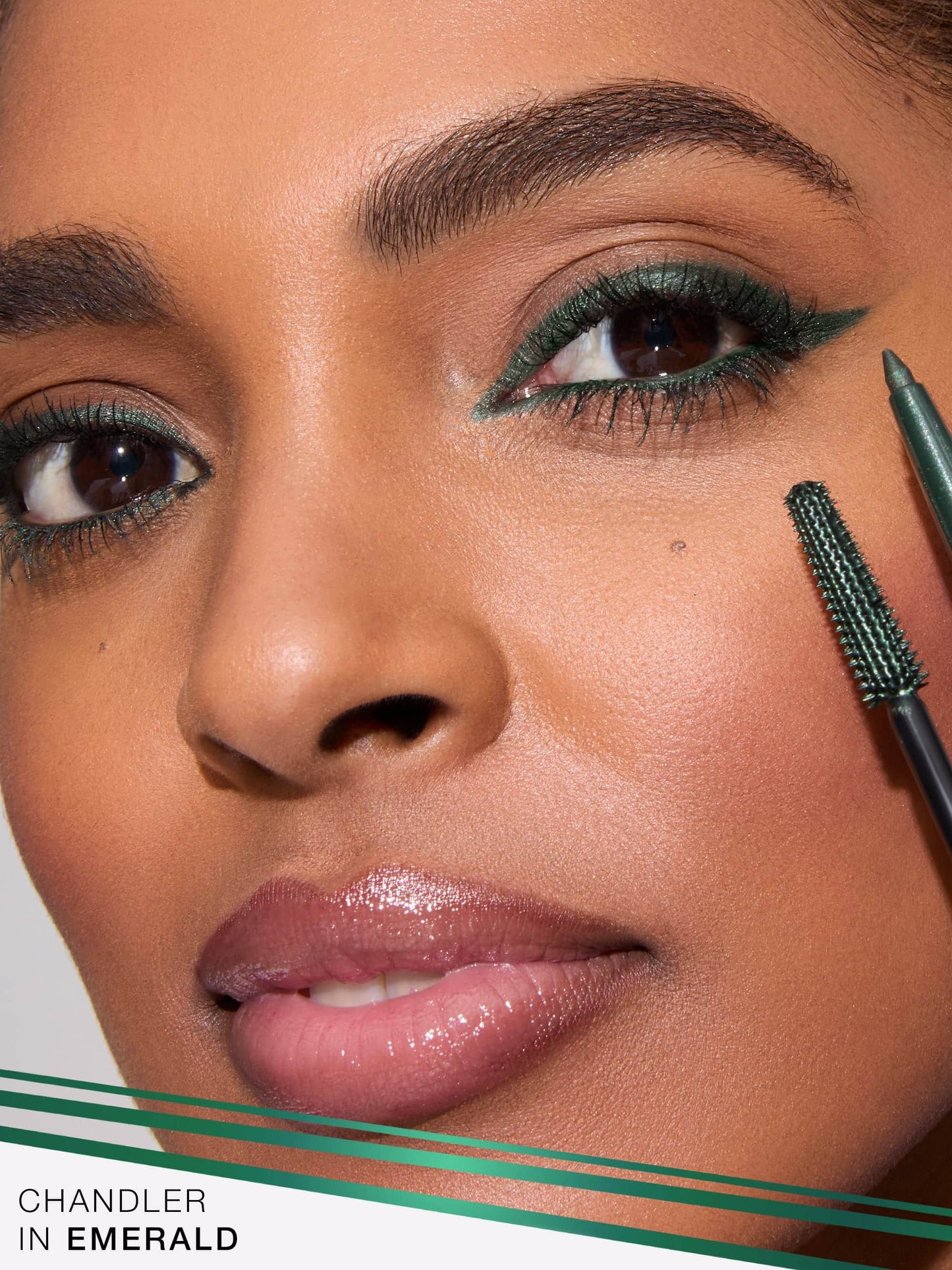 Close-up of a person applying eyeliner with a brush, featuring the brand 'Chandler' in Emerald.