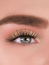 Close-up of a woman's eye with long, dark eyelashes and pink eyeshadow.