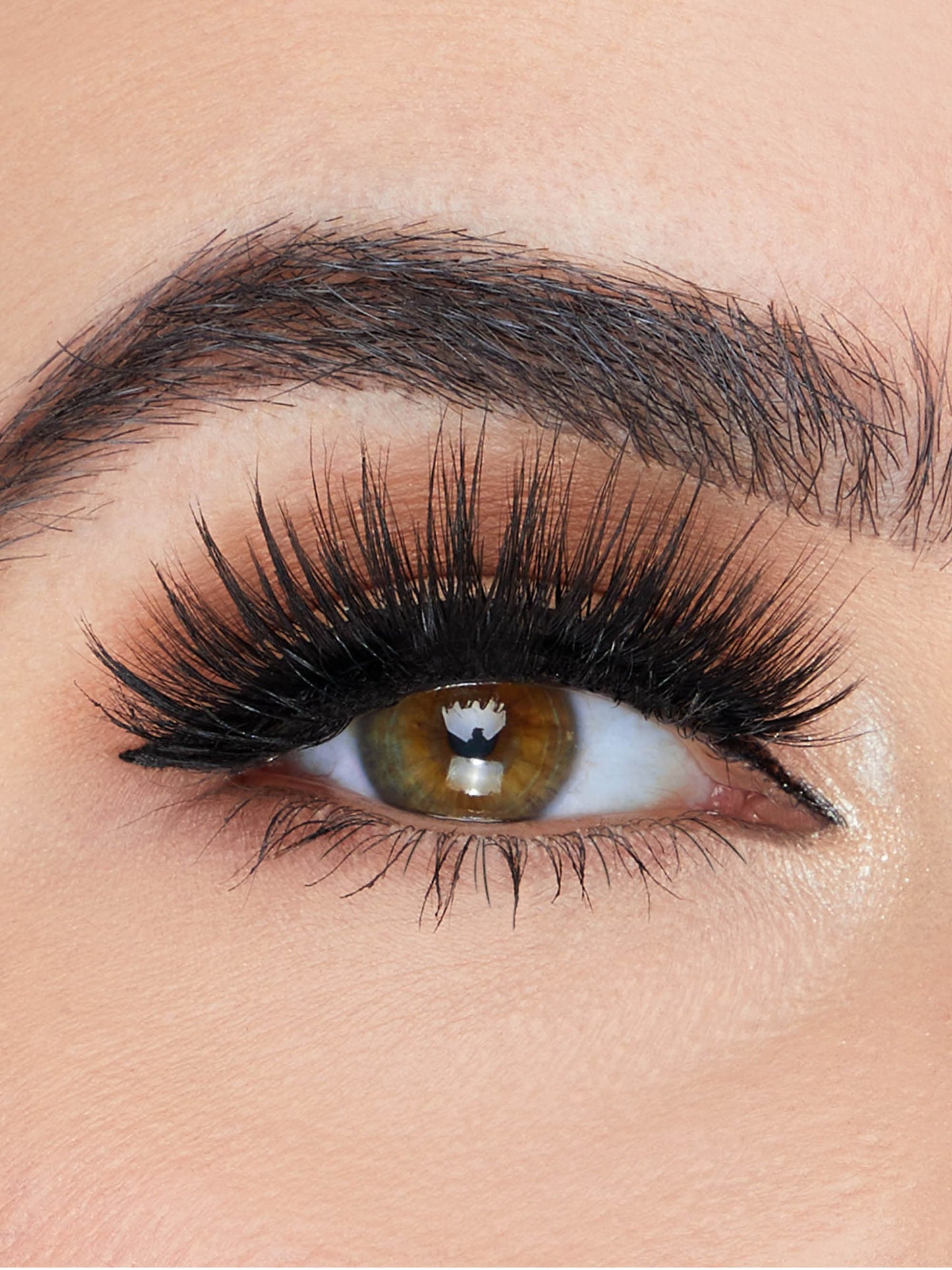Close-up of an eye with long, dark eyelashes and brown makeup.